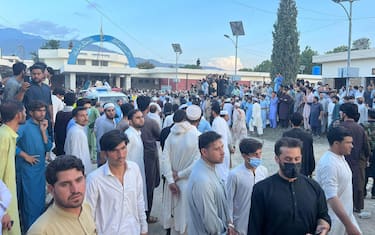 epa10777368 People gather outside a hospital after a blast targeting a gathering of Islamic political party Jamiat Ulma-e-Islam (JUI-F) in Bajaur, Pakistan, 30 July 2023. At least 20 people were killed and several injured in an explosion at the JUI-F workers convention in Khar, police said.  EPA/HANIFULLAH KHAN BEST QUALITY AVAILABLE