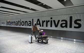 TOPSHOT - A passenger wearing a face mask as a precautionary measure against COVID-19, walks through the arrivals hall after landing at London Heathrow Airport in west London, on January 15, 2021. - International travellers will need to present proof of a negative coronavirus test result in order to be allowed into England, or face a £500 ($685, 564 euros) fine on arrival, from January 18. (Photo by Daniel LEAL / AFP) (Photo by DANIEL LEAL/AFP via Getty Images)