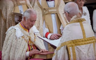 King Charles III Coronation, seated in ceremonial robes, takes solemn Coronation Oaths, with Archbishop Justin Welby, touching The Holy Bible engraved with his Sovereigns Cypher and date, during the coronation service ceremony at Westminster Abbey Westminster London UK May 6th 2023