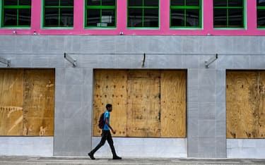 A man walks past boarded up shop windows before the arrival of Hurricane Beryl in Bridgetown, Barbados on June 30, 2024. Beryl, the first hurricane of the 2024 Atlantic season, strengthened into an "extremely dangerous" Category 4 storm Sunday as it threatened the southeast Caribbean with potentially life-threatening winds and storm surge, US trackers said. (Photo by CHANDAN KHANNA / AFP) (Photo by CHANDAN KHANNA/AFP via Getty Images)