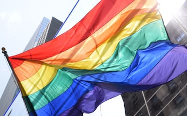 Rainbow flag waving in front of a corporate building in a big city. LGBTQ parade. Equality and love for all.