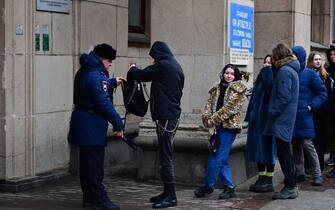 A police officer checks a man as he and other people queue outside a polling station during Russia's presidential election in Saint Petersburg on March 17, 2024. Russian opposition has called on people to head to the polls on March 17, 2024, at noon, in large numbers to overwhelm polling stations, in a protest which they hope will be a legal show of strength against President Vladimir Putin. (Photo by Olga MALTSEVA / AFP)