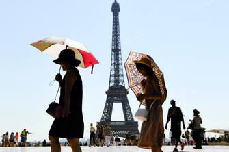 (FILES) In this file photo taken on August 03, 2018  tourists use umbrellas to shelter from the sun as they walk at Esplanade du Trocadero in front of The Eiffel Tower in Paris. - The Eiffel Tower will reopen on July 16, 2021, after several months of closure due to the coronavirus pandemic, the Paris landmark's operator said on July 15, 2021, with a limited number of 10,000 a day to meet distancing requirements. (Photo by ALAIN JOCARD / AFP)