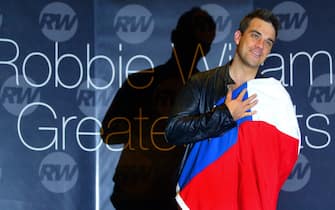 British artist Robbie Williams, poses for photographers with the Chilean flag during a press conference in Santiago, 24 November 2004. Williams arrived in Chile in the framework of a Latin American tour.   AFP PHOTO/MARTIN BERNETTI (Photo by Martin BERNETTI / AFP) (Photo by MARTIN BERNETTI/AFP via Getty Images)