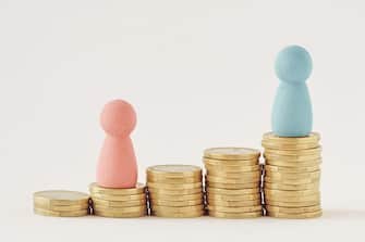 Pink and blue pawns on raising piles of coins - Gender pay gap concept