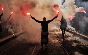 A protester, holding smoke flares, participates in a demonstration on the third day of nationwide rallies organised since the start of the year, against a deeply unpopular pensions overhaul in Nice, south eastern France on February 7, 2023. - France braced for new strikes and mass demonstrations against French President's proposal to reform French pensions, including hiking the retirement age from 62 to 64 and increasing the number of years people must make contributions for a full pension on February 7, 2023, a day after lawmakers started debating the contested bill. (Photo by Valery HACHE / AFP) (Photo by VALERY HACHE/AFP via Getty Images)