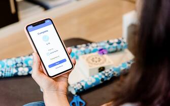 woman sending money to a friend through a cell phone for a gift from a mutual friend