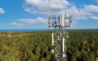 telecommunication tower with antennas for 5g network on forest and blue sky background. mobile internet broadcast