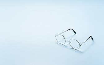 Minimalistic Simple Round Eyeglasses Side View on Light Blue Background With Copy Space.
