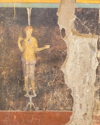 Un particolare dell'imponente salone da banchetto, dalle eleganti pareti nere decorate con soggetti mitologici ispirati alla guerra di Troia, tra gli ambienti recentemente portati alla luce durante le attività di scavo in corso nell'insula 10 della Regio IX di Pompei e oggi completamente visibile in tutta la sua maestosità. Un ambiente raffinato in cui il tema dominante delle decorazioni sembra essere quello dell'eroismo,  del fato e della possibilità che l'uomo ha di poter cambiare il proprio destino. Oltre a Elena e Paride, indicato in un'iscrizione greca tra le due figure con il suo altro nome 'Alexandros', appare sulle pareti del salone la figura di Cassandra, figlia di Priamo, in coppia con Apollo. Roma, 11 aprile 2024 ANSA/ Ufficio stampa del Ministero della cultura ANSA PROVIDES ACCESS TO THIS HANDOUT PHOTO TO BE USED SOLELY TO ILLUSTRATE NEWS REPORTING OR COMMENTARY ON THE FACTS OR EVENTS DEPICTED IN THIS IMAGE; NO ARCHIVING; NO LICENSING NPK