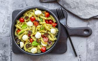 Nudelsalat mit grünem Pesto, Tomaten, Mozzarella, Oliven und Basilikum