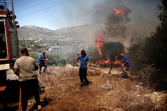 epa10751577 Local firefighters operate during a wildfire at Kouvaras area in Attica, Greece, 17 July 2023. Firefighting forces are battling a blaze that broke out in the Kouvaras area in Attica, while a warning was sent via the emergency number 112 to evacuate several settlements in southeast Attica. A force of 55 firefighters and 20 fire engines, two units on foot and 31 Romanian firefighters with five water tankers have been deployed to put out the fire, assisted by six fire-fighting aircraft and four helicopters from the air.  EPA/YANNIS KOLESIDIS