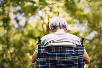 rear view of a senior man sitting in  wheelchair with head down