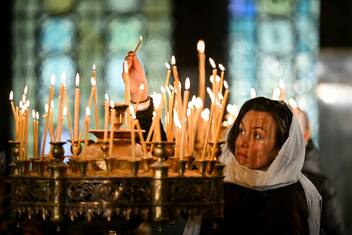 An Orthodox Christian believer lights a candle during a Christmas mass at the golden-domed Alexander Nevski Cathedral, in Sofia, on December 25, 2024. Bulgaria, unlike some other fellow Orthodox countries, celebrates Christmas on December 25th. (Photo by Nikolay DOYCHINOV / AFP) (Photo by NIKOLAY DOYCHINOV/AFP via Getty Images)