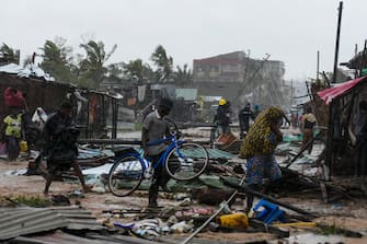 epa10517521 A man walks among the debris with his bycicle on a flooded street near Quelimane, as the storm Freddy hits Mozambique, 12 March 2023. The provincial capital of Quelimane will be the largest urban area closest to the cyclone's point of arrival on the mainland, and its radius (of about 300 kilometres) is expected to extend from Marromeu to Pebane, then moving inland towards Cherimane and southern Malawi. This is one of the longest lasting storms ever, after it formed at the beginning of February in the Asian seas, crossing the entire Indian Ocean to the east African coast.  EPA/ANDRE CATUEIRA