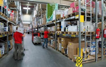 Two workers in a warehouse with high shelves.