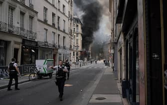 French policemen secure the area a smoke rises from a building partly collapsed at Place Alphonse-Laveran in the 5th arrondissement of Paris, on June 21, 2023. (Photo by ABDULMONAM EASSA / AFP) (Photo by ABDULMONAM EASSA/AFP via Getty Images)