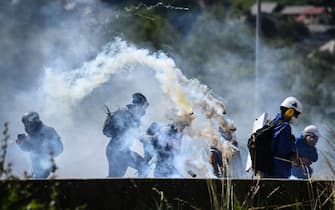 TOPSHOT - Protestors run from launched tear gas canisters during clashes with security forces at a demonstration against the construction of a high-speed rail line between Lyon and Torino, in La Chapelle, near Modane, in the French Alps' Maurienne valley, on June 17, 2023. Hundreds of oponents to the Lyon-Torino high-speed rail line demonstrated on June 17 despite a ban on the gathering, of which the details are yet to be determined and despite a heavy police presence in the valley. They set up a makeshift camp on land lent by the municipality of La Chapelle, outside the ban zone announced the day before by the Savoie prefecture. (Photo by OLIVIER CHASSIGNOLE / AFP) (Photo by OLIVIER CHASSIGNOLE/AFP via Getty Images)