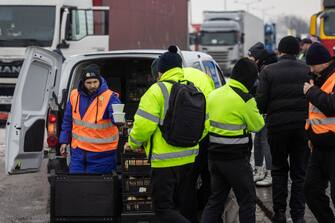 Volounteer from the World Central Kitchen organisation Maciej (L) provides hot meals to Ukrainian truck drivers, on the parking lot near Korczowa Polish-Ukrainian border crossing, on December 5, 2023. In a Polish car park near the Ukrainian border, truck drivers stranded by a month-long blockade that has caused disruption and a row with Ukraine shoveled snow off their vehicles.
Around 100 truckers have been stuck in Korczowa, one of the crossings blocked by protesting Polish hauliers who complain about what they say is unfair competition from Ukrainian companies. (Photo by Wojtek Radwanski / AFP) (Photo by WOJTEK RADWANSKI/AFP via Getty Images)