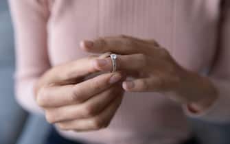 Close up woman taking off wedding ring, divorce concept