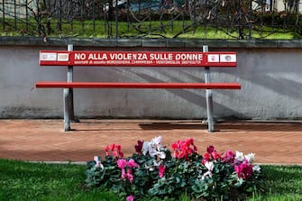 A red bench with the inscription: "No to violence against women" in a street of Bordighera, Imperia, Liguria, Italy