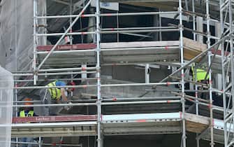 Operai edili al lavoro sulla faccaita di  un palazzo ricoperto da ponteggi, Milano, 14 giugno 2022. ANSA/DANIEL DAL ZENNARO