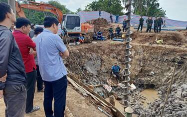 Rescuers look down into the site of where a 10-year-old boy is thought to be trapped in a 35-metre deep shaft at a bridge construction area in Vietnam's Dong Thap province on January 2, 2023. - Hundreds of rescuers in Vietnam battled January 2 to free a 10-year-old boy who fell into a 35-metre deep hole on a construction site two days ago. (Photo by AFP) (Photo by STR/AFP via Getty Images)