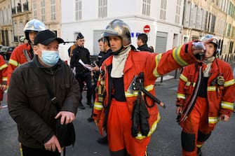 A firefighter gestures as inhabitants of the 'rue Trivoli' are evacuated after a building collapsed in the same street, in Marseille, southern France, on April 9, 2023. - "We have to be prepared to have victims," the mayor of Marseille warned on April 9, 2023 after a four-storey apartment building collapsed in the centre of France's second city, injuring five people, according to a provisional report. (Photo by NICOLAS TUCAT / AFP) (Photo by NICOLAS TUCAT/AFP via Getty Images)