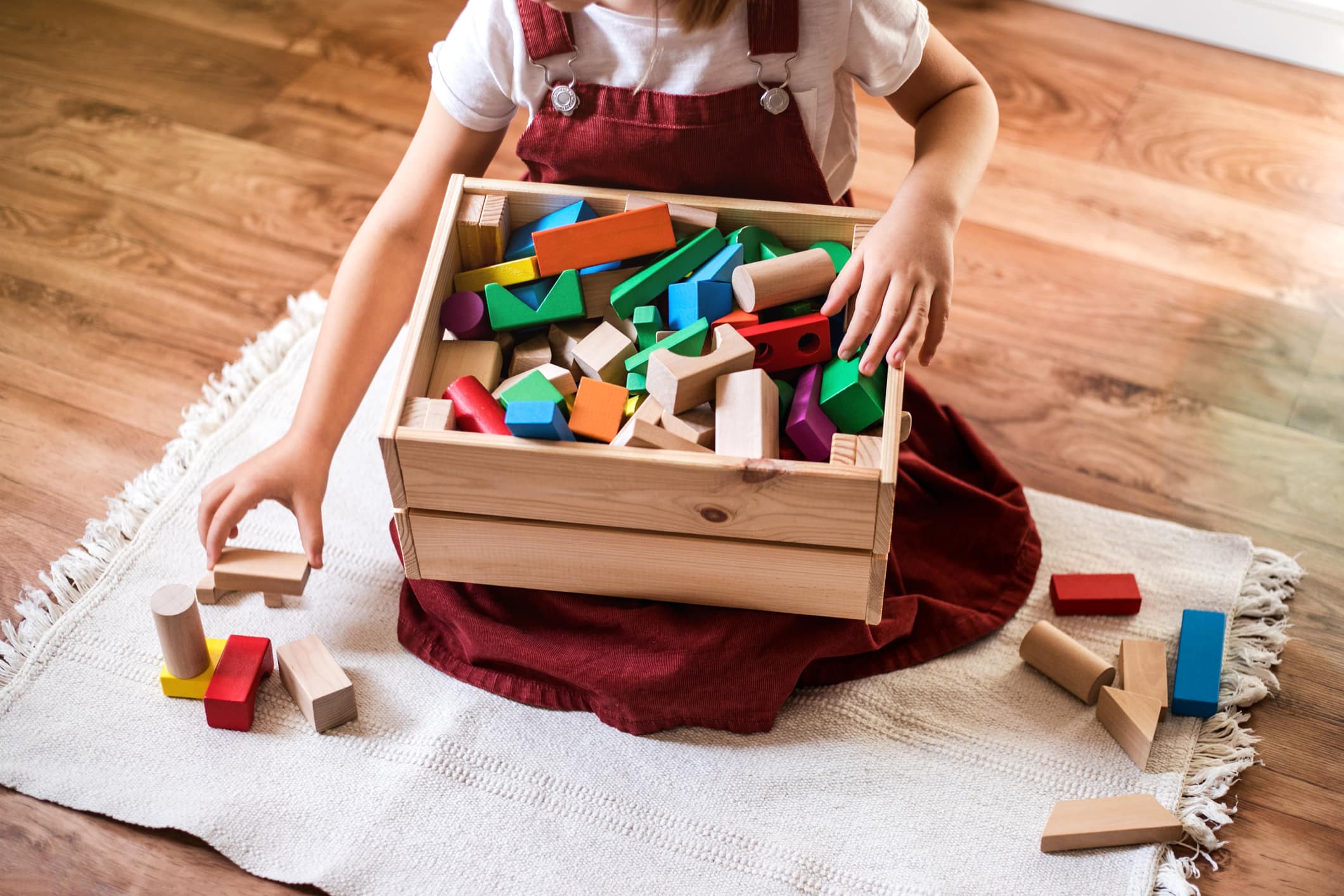 Little girl cleaning up the toy box at home. Child's space organization.