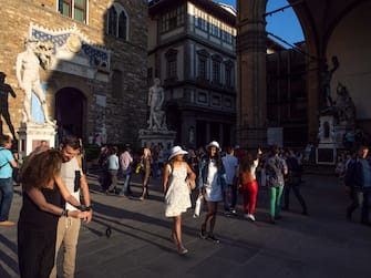 Florence, Italy May 12th 2018. Tourists walking and posing for snapshot in Piazza della Signoria , in front of the David di Michelangelo reproduction. The original one is preserved in the Galleria dell'Accademia.