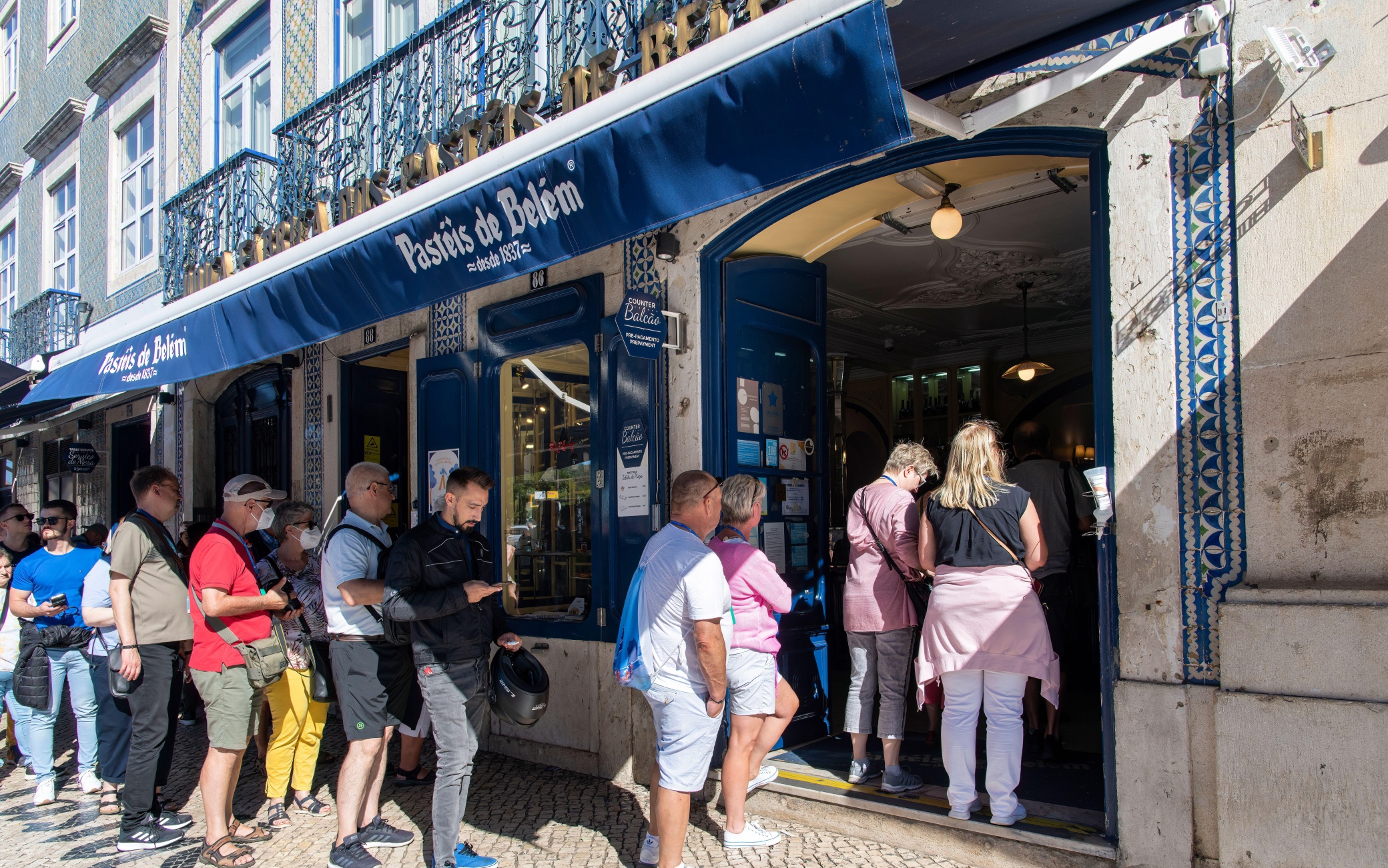 Lisbon, Portugal-October 2022: Entrance view with a line of people waiting to go inside of pastry store Pastéis de Belem