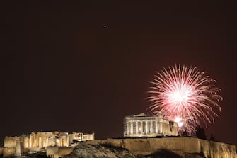 epaselect epa11051410 Fireworks illuminate the Athenian sky over the Acropolis hill, during the New Year celebrations in Athens, Greece, 01 January 2024.  EPA/GEORGE VITSARAS