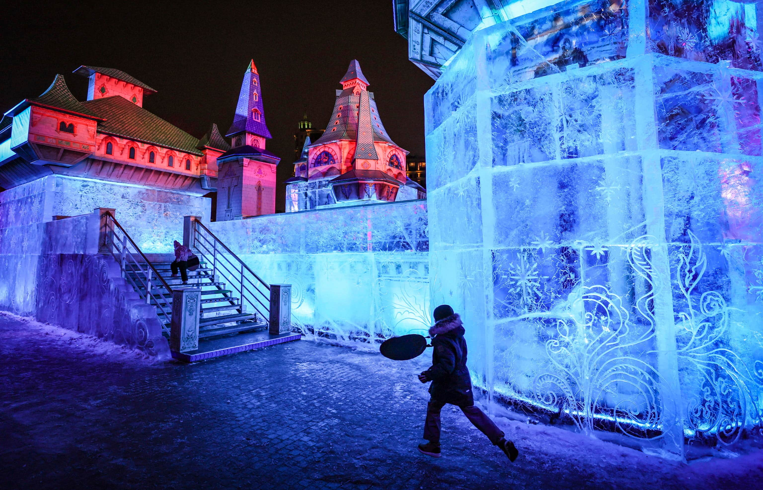 epa11794058 A boy runs near the ice installation 'Castle of Miracles' during the festival of ice sculptures 'Snow and Ice in Moscow' at Gorky Park in Moscow, Russia, 26 December 2024. The festival will last until 20 January 2025. Russians are preparing to celebrate New Year's Eve on 31 December and Christmas, observed on 07 January, according to the Russian Orthodox Julian calendar.  EPA/YURI KOCHETKOV