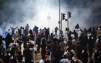 epa10717453 People run from tear gas as they clash with French riot police on the sidelines of a march in the memory of 17-year-old Nahel, who was killed by French Police in Nanterre, near Paris, France, 29 June 2023. Violence broke out after the police fatally shot a 17-year-old during a traffic stop in Nanterre on 27 June. According to the French interior minister, 31 people were arrested with 2,000 officers being deployed to prevent further violence.  EPA/YOAN VALAT