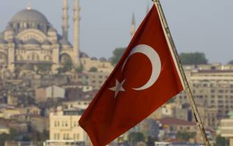 Turkish Flag on back of boat on the Bosphorus and Mosque on hillside just above