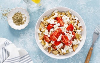 Dakos or koukouvagia salad. Classic recipe Cretan barley rusk salad with fresh tomato, mizithra cheese and oregano. Traditional mediterranean Greek cu