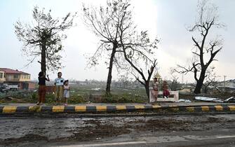 Local residents stand by a road next to broken trees in Sittwe, in Myanmar's Rakhine state, on May 15, 2023, after cyclone Mocha made a landfall. Cyclone Mocha made landfall between Cox's Bazar in Bangladesh and Myanmar's Sittwe carrying winds of up to 195 kilometres (120 miles) per hour, the biggest storm to hit the Bay of Bengal in more than a decade. (Photo by Sai Aung MAIN / AFP) (Photo by SAI AUNG MAIN/AFP via Getty Images)