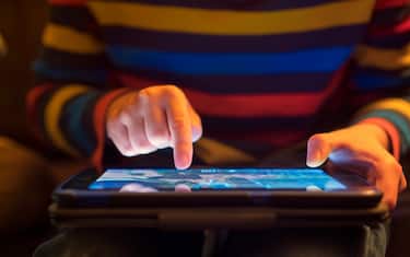 Close up of a young boy using a tablet computer, his finger hovering over it as he's about to touch the screen.
