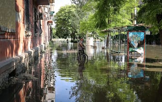 A local resident stands with his bicycle in a flooded street in the town of Kherson,  following flooding caused by damage sustained at the Kakhovka HPP dam, on June 6, 2023. The partial destruction on June 6, of the major Russian-held dam in southern Ukraine unleashed a torrent of water that flooded two dozen villages forcing mass evacuation, sparking fears of a humanitarian disaster near the war's front line. Moscow and Kyiv traded blame for ripping a gaping hole in the Kakhovka dam as expectations built over the start of Ukraine's long-awaited offensive. (Photo by STRINGER / AFP)