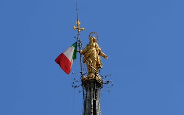 Tricolore della bandiera italiana issatosulla guglia maggiore del Duomo di Milano, accanto alla Madonnina,Milano, 24 aprile 2020, ANSA / PAOLO SALMOIRAGO
