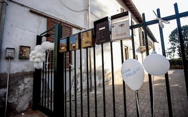 Palloncini appesi al cancello dell'abitazione dove è deceduta una bambina di 18 mesi in via Parea a Milano, 21 luglio 2022.ANSA/MOURAD BALTI TOUATI