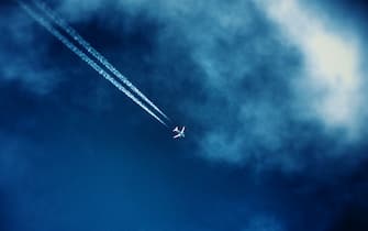 Airliner track in the clouds in the dark blue sky seen from the bottom in the afternoon