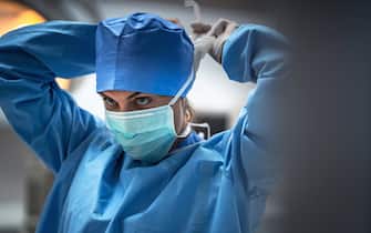 The surgeon is wearing a mask to prevent infection before surgery.
