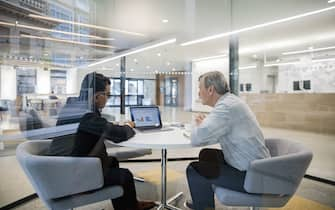 Male loan manager with laptop meeting with client in bank branch office