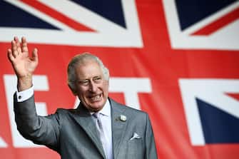 (FILES) Britain's King Charles III waves to the crowd under a giant Union flag during a visit to a festival in celebration of British and French culture and business at Place de la Bourse in Bordeaux, southwestern France, on September 22, 2023. Britain's King Charles III will attend hospital next week for a corrective procedure to treat an enlarged prostate, Buckingham Palace said January 17, 2024. (Photo by Christophe ARCHAMBAULT / POOL / AFP)
