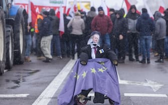 A straw-made dummy with the face of EU agricultural commissioner Janusz Wojciechowski sits in a wheelchair coverd with the EU flag, as farmers block the access to the Polish-Ukrainian border crossing in Dorohusk, eastern Poland on February 9, 2024, during a farmers' protest across the country against EU politics and Ukrainian agricultural products allowed on EU market at low prices. (Photo by Wojtek Radwanski / AFP) (Photo by WOJTEK RADWANSKI/AFP via Getty Images)