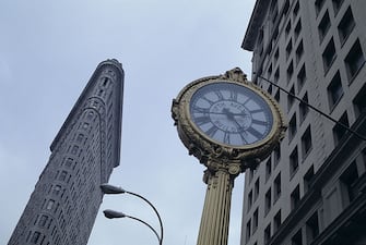 Foresightening view from below of a metropolitan clock and the Flatiron Building, the skyscraper designed by American architect Daniel Burnham in 1902. New York, 1990s  (Photo by Fabrizio Carraro\Archivio Fabrizio Carraro\Mondadori via Getty Images)