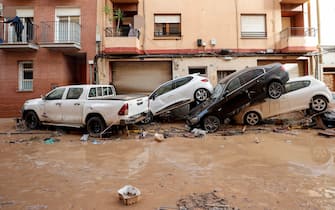 epa11692829 Residents look out from their balconies at damaged cars piled up in the flood-hit municipality of Paiporta, in the province of Valencia, Spain, 30 October 2024. The intense rainfall impacting the eastern part of the country resulted in at least 70 lives being lost in the province of Valencia and neighboring provinces due to the flooding. The State Meteorological Agency (AEMET) issued orange and red alerts for rainfall in multiple regions of east and southern Spain due to a DANA (isolated depression at high levels) phenomenon. The mayor of Paiporta, located about ten kilometers southwest of Valencia, confirmed that at least 34 people died in the municipality due to the flooding.  EPA/MANUEL BRUQUE