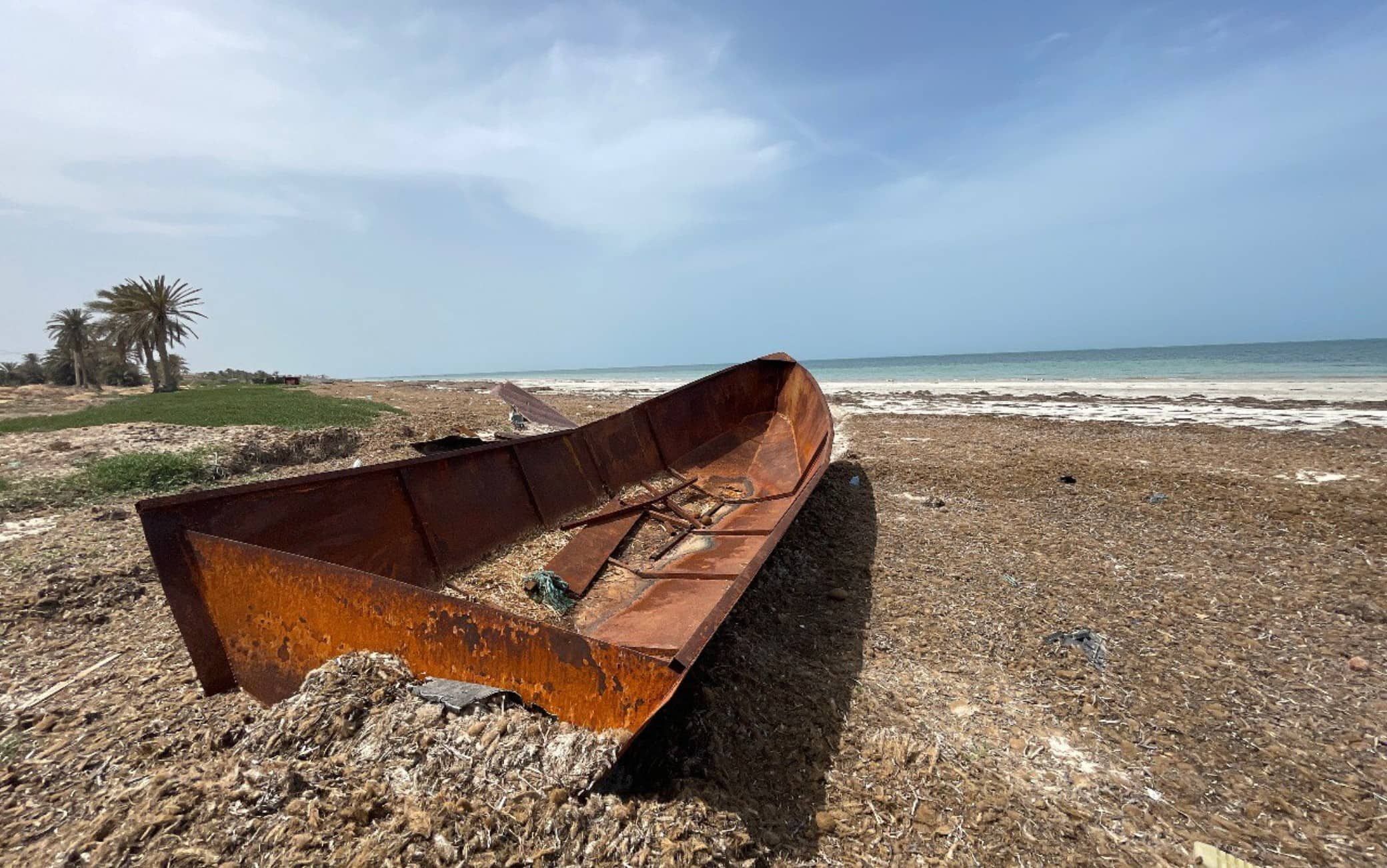 Di nuovo a terra, verso la Tunisia e l’Italia   Una volta rientrati in porto in Libia, tutti i migranti finiscono in prigione, per questo, se riescono ad uscire, cercano di scappare verso la Tunisia. Qui, almeno, la paga è migliore, non si rischia la prigione e il razzismo è meno accentuato, nonostante il discorso di febbraio del presidente Saied, che si è richiamato alle teorie sulla sostituzione etnica, abbia scatenato un’ondata di attacchi xenofobi verso i neri. Ma, soprattutto, la Tunisia è molto più vicina all’Italia, in particolare a Lampedusa. Il problema, qui, è che da tempo ormai è all’opera una specie di criminalità organizzata che costringe i migranti neri a partire su piccoli barchini in metallo prodotti artigianalmente dai trafficanti, con saldature fatte a mano e motori da pochi cavalli. Un business particolarmente redditizio, perché il passaggio costa dai 1.000 ai 1.500 euro e le barche vengono riempite di persone fino all’orlo. Anche 30 o 40 migranti salgono a bordo. Questi barchini, ci raccontano i pescatori e gli abitanti dei villaggi sul mare a nord di Sfax, in troppi casi affondano subito dopo essere partiti. E il mare restituisce i cadaveri senza nome di chi magari era partito da casa 4 o 5 anni fa.   