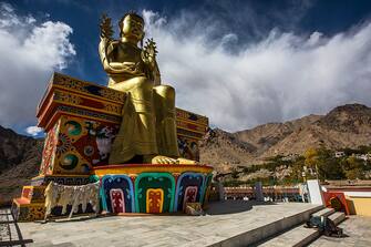 LEH, INDIA - OCTOBER 4:  A Buddhist devotee prays at the base of a 25m (75ft) stautue of Buddha at the Likir monastery on October 4, 2012 near to Leh in Ladakh, India. Ladakh, nestled between the Kunlun mountain range in the north and the main Great Himalayas to the south, was once an ancient Buddhist Kingdom and for over half a century now, a strategic military outpost for India. Ladakh, sharing borders with both China and Pakistan, has seen an increase in tourism over the last few years, an alternative to Nepali Himalayan treks. (Photo by Daniel Berehulak/Getty Images)